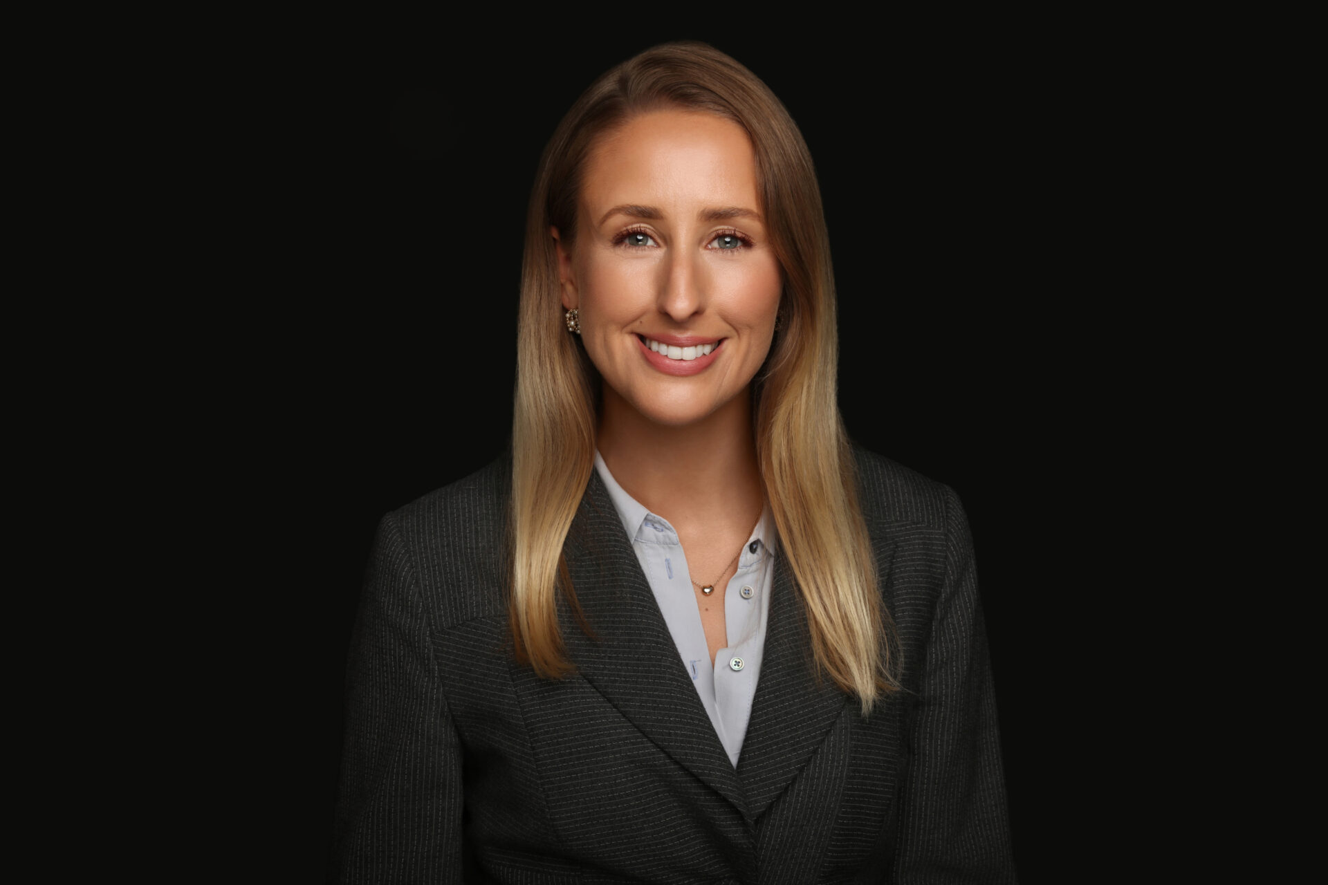 A woman with long brown hair wearing a dark suit jacket