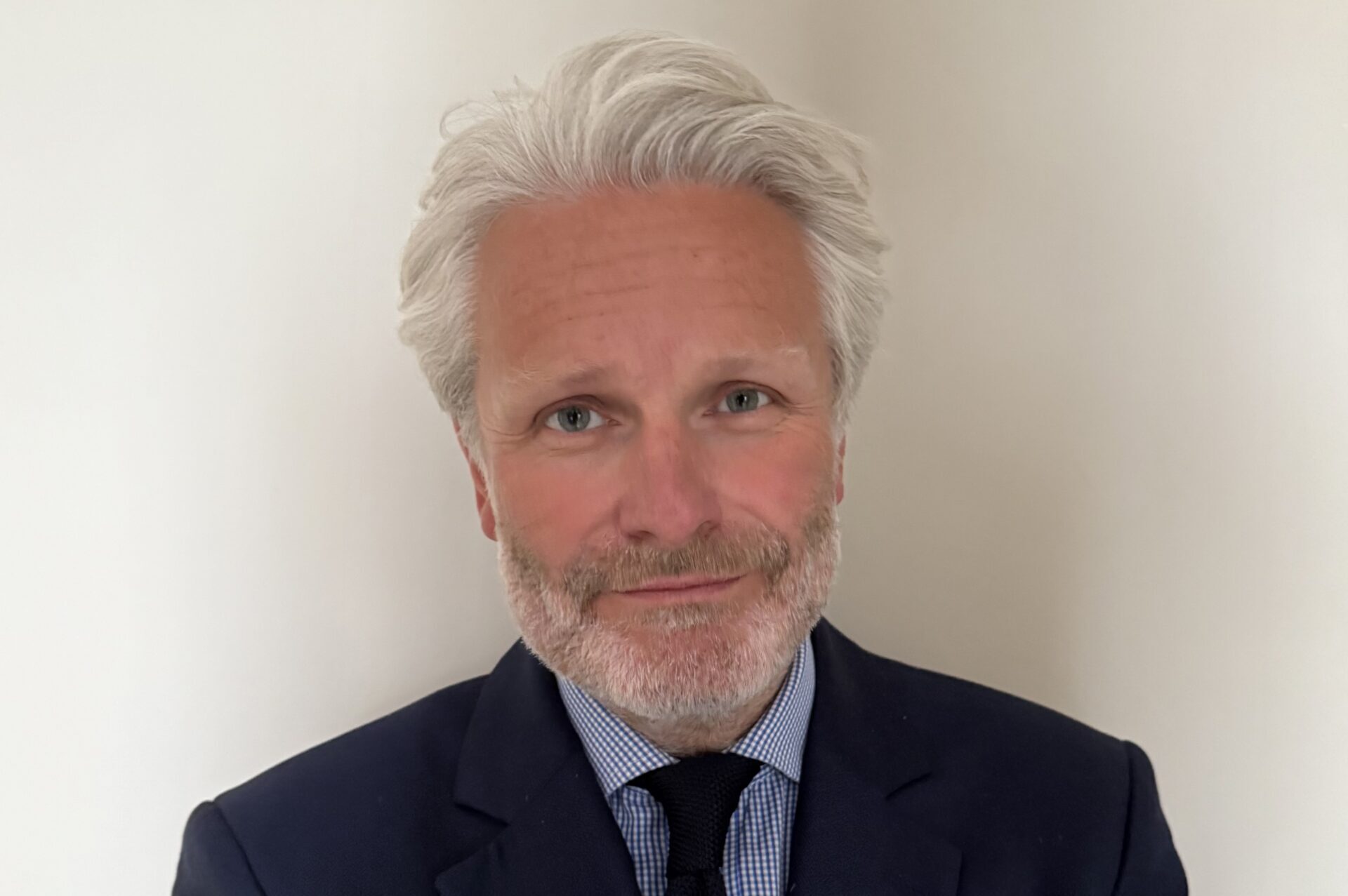 A man with grey hair and a beard wearing a suit and tie