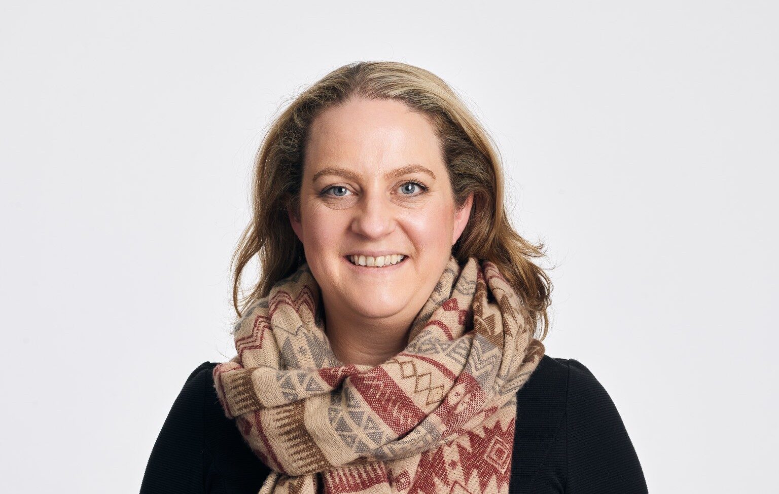 A smiling woman wearing a large scarf