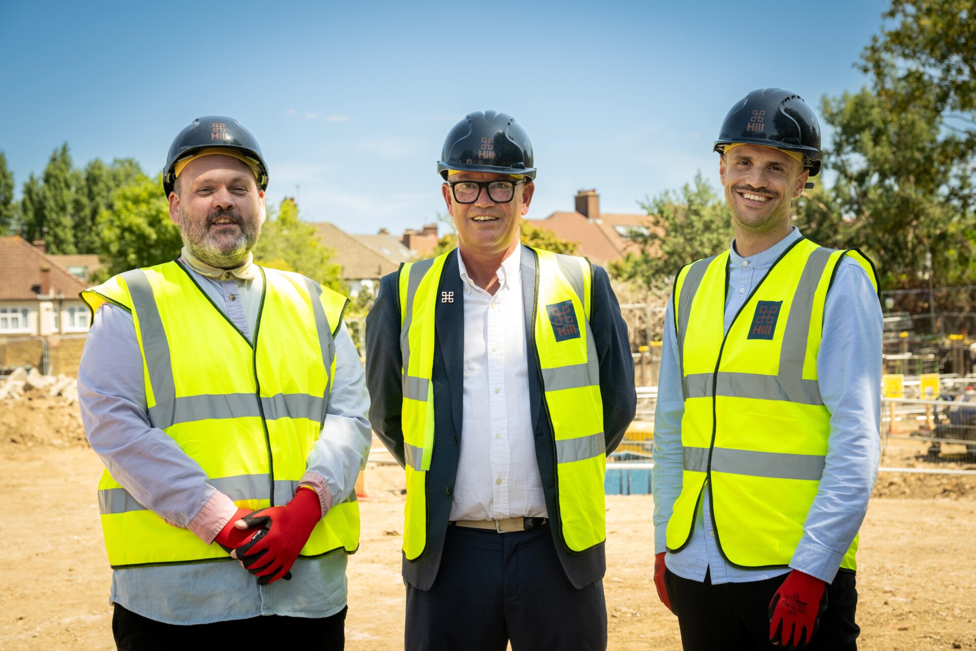 Three smiling men wearing high vis jackets and hard hats