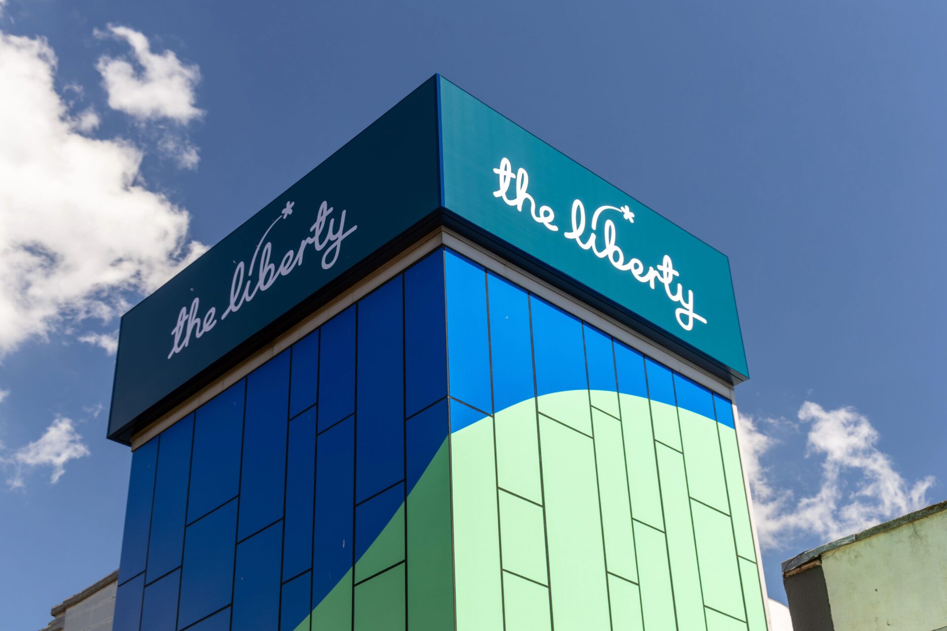 The top of a blue and green tower featuring The Liberty sign