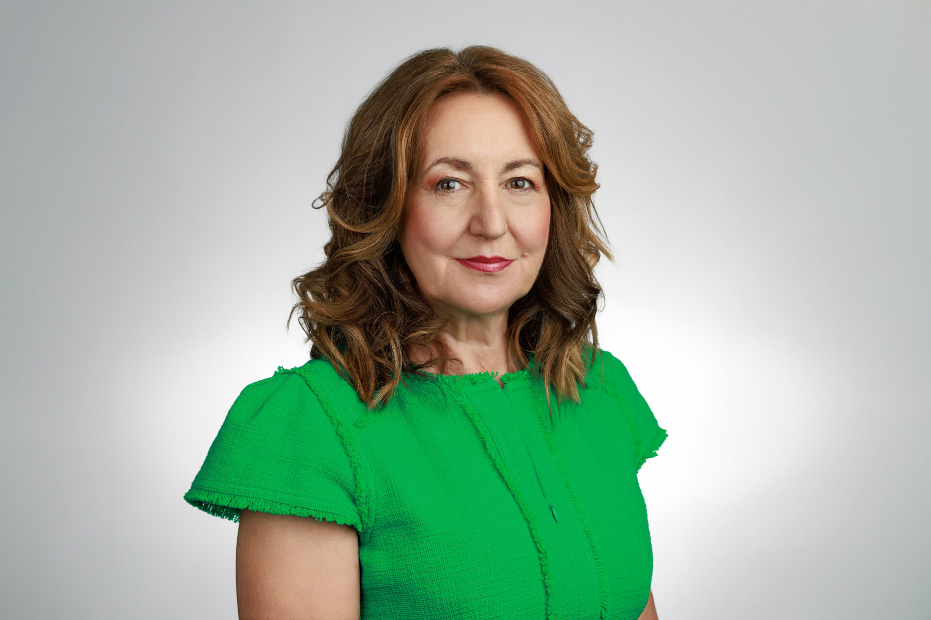 A woman with wavy brown hair wearing a green top