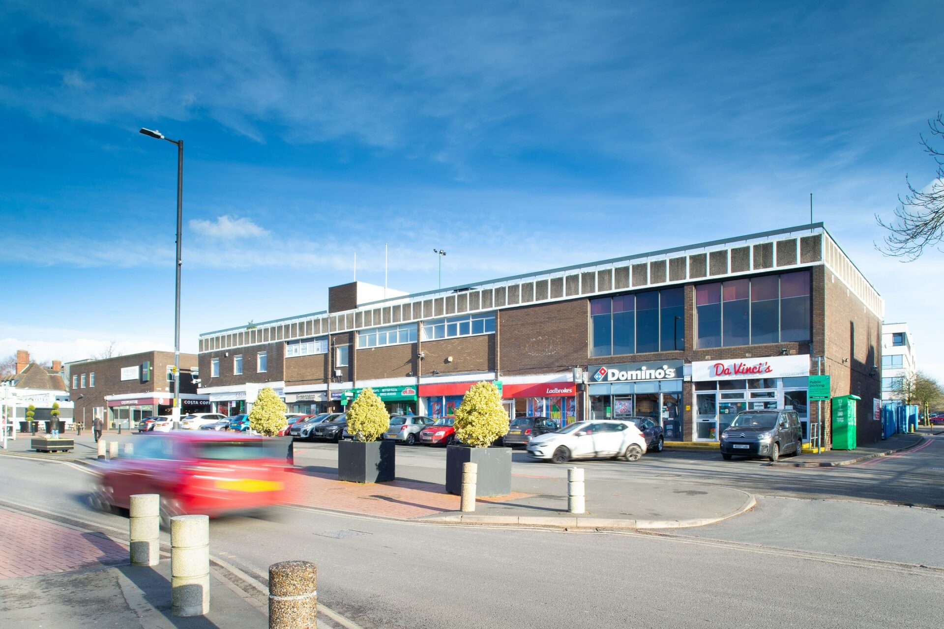 A shopping parade featuring a row of retail units with a main road in front