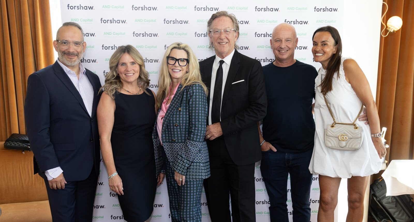Three men and three women stood in front of a white advertising board