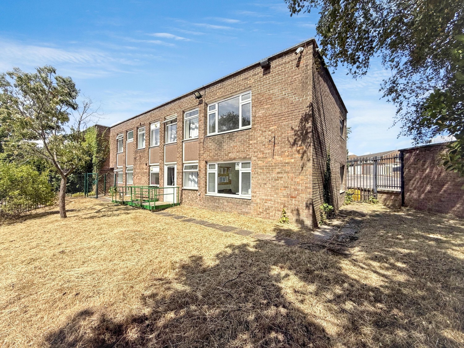 A brick built residential block with a grass lawn in front