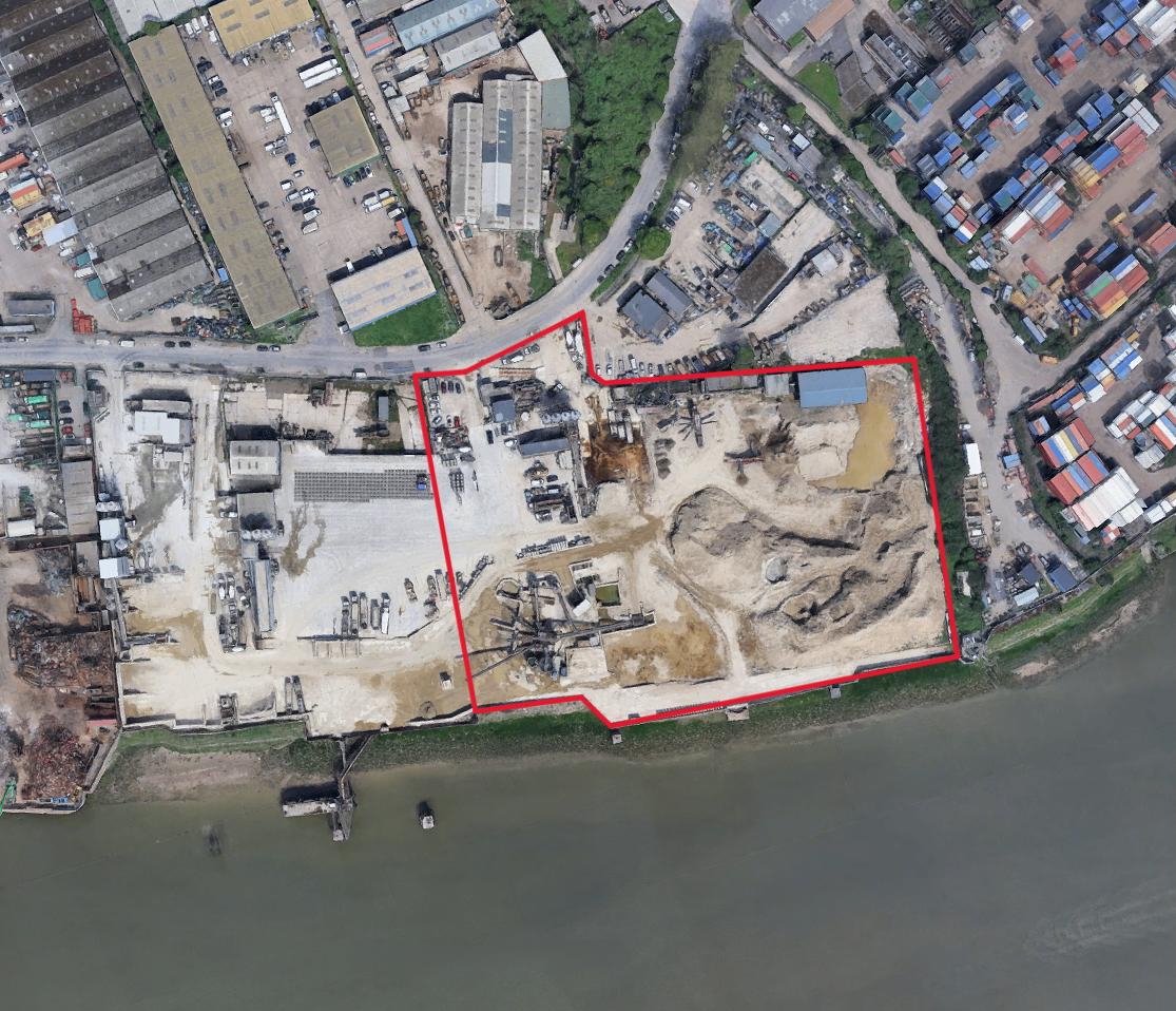 Aerial view of a wharf site marked in red alongside a river