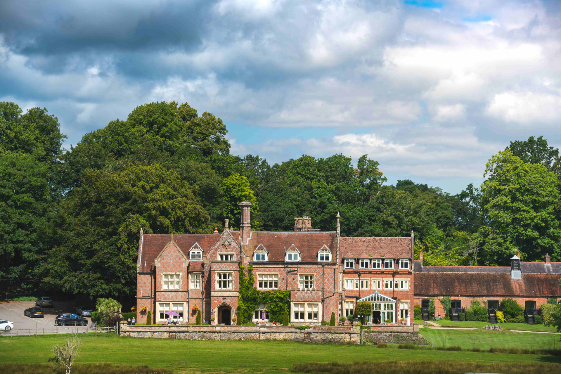 A grand old manor house with a lawn in the foreground and a wooded area behind