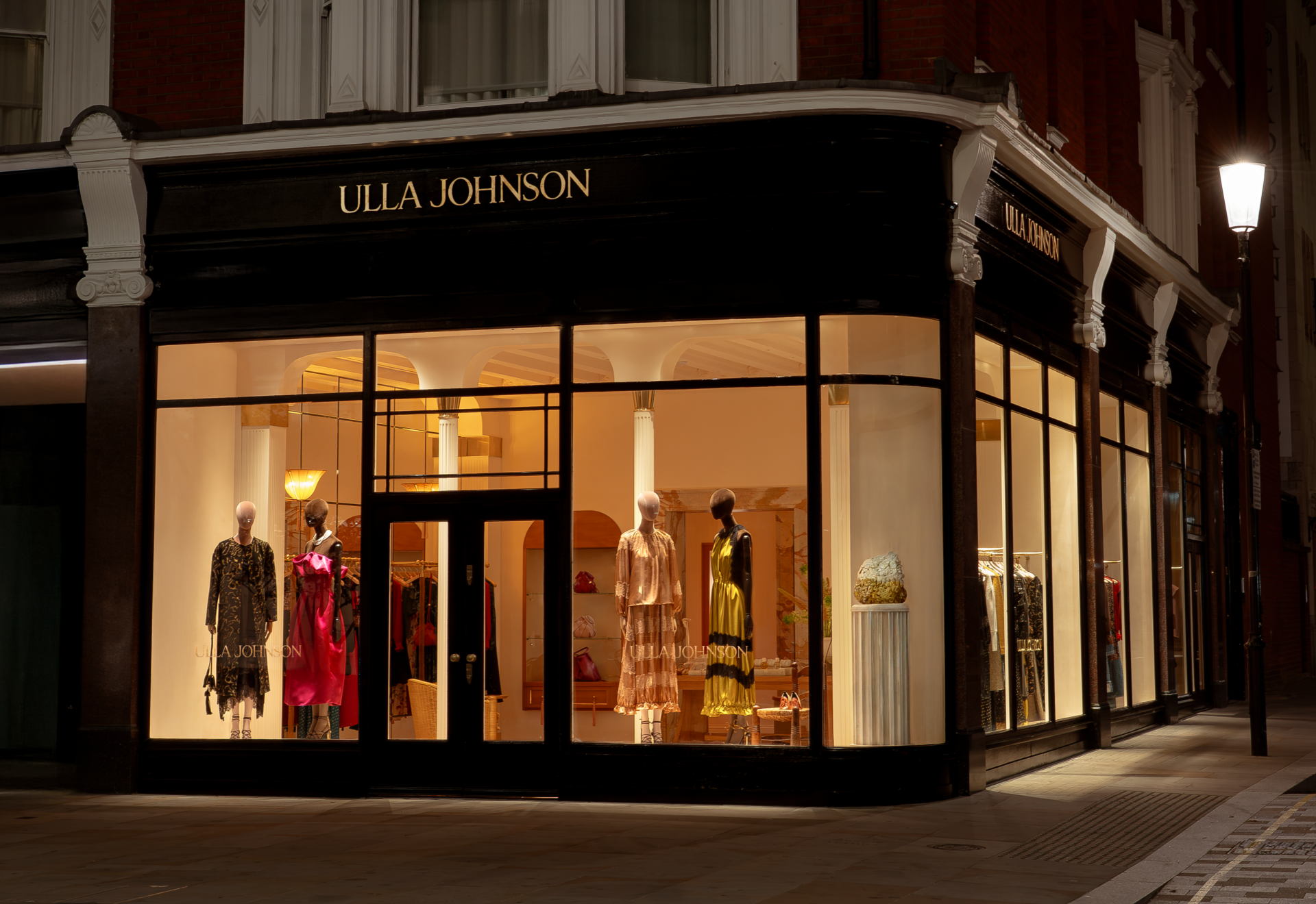 Exterior of a retail store at night featuring a sign saying Ulla Johnson