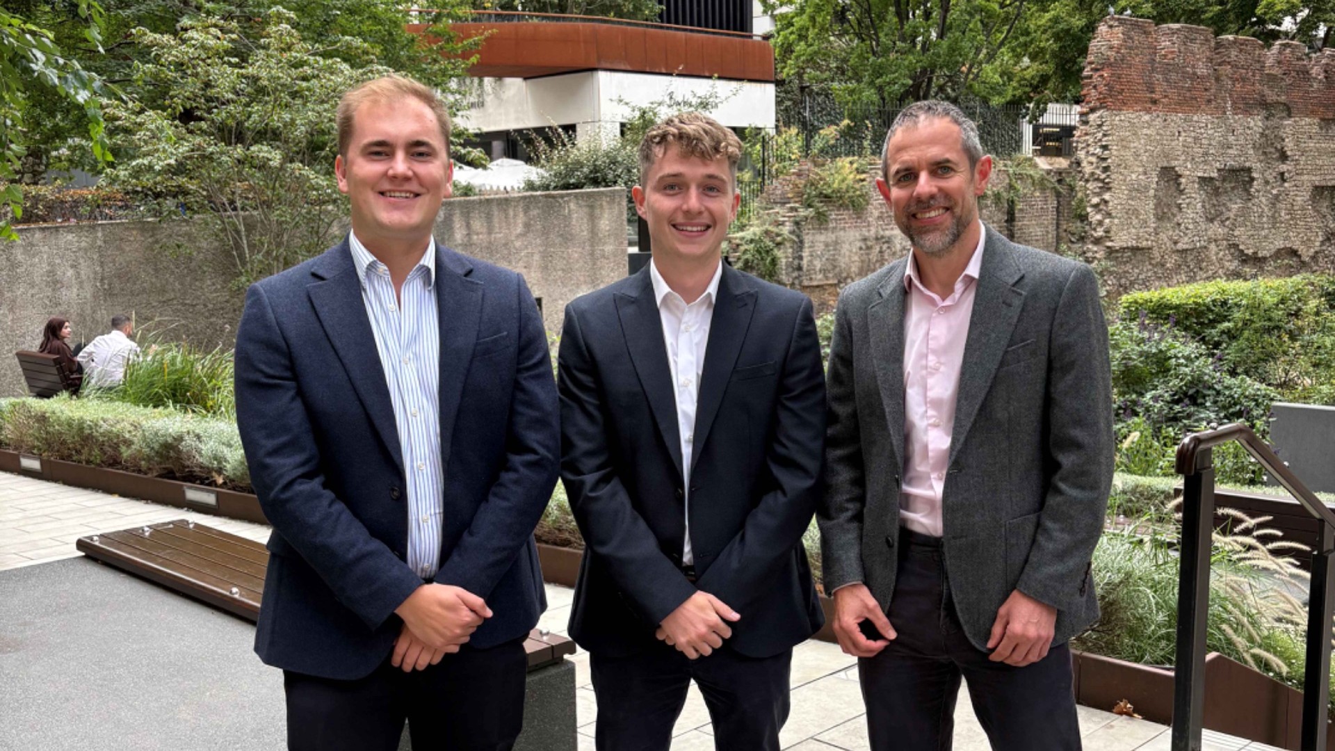 Tom Martin, Ian Whittaker and Nathan Pask stand together outdoors in a landscaped London courtyard