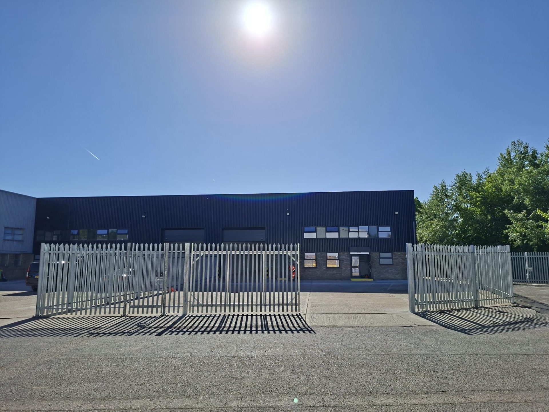 Industrial unit behind a metal security fence on a sunny day