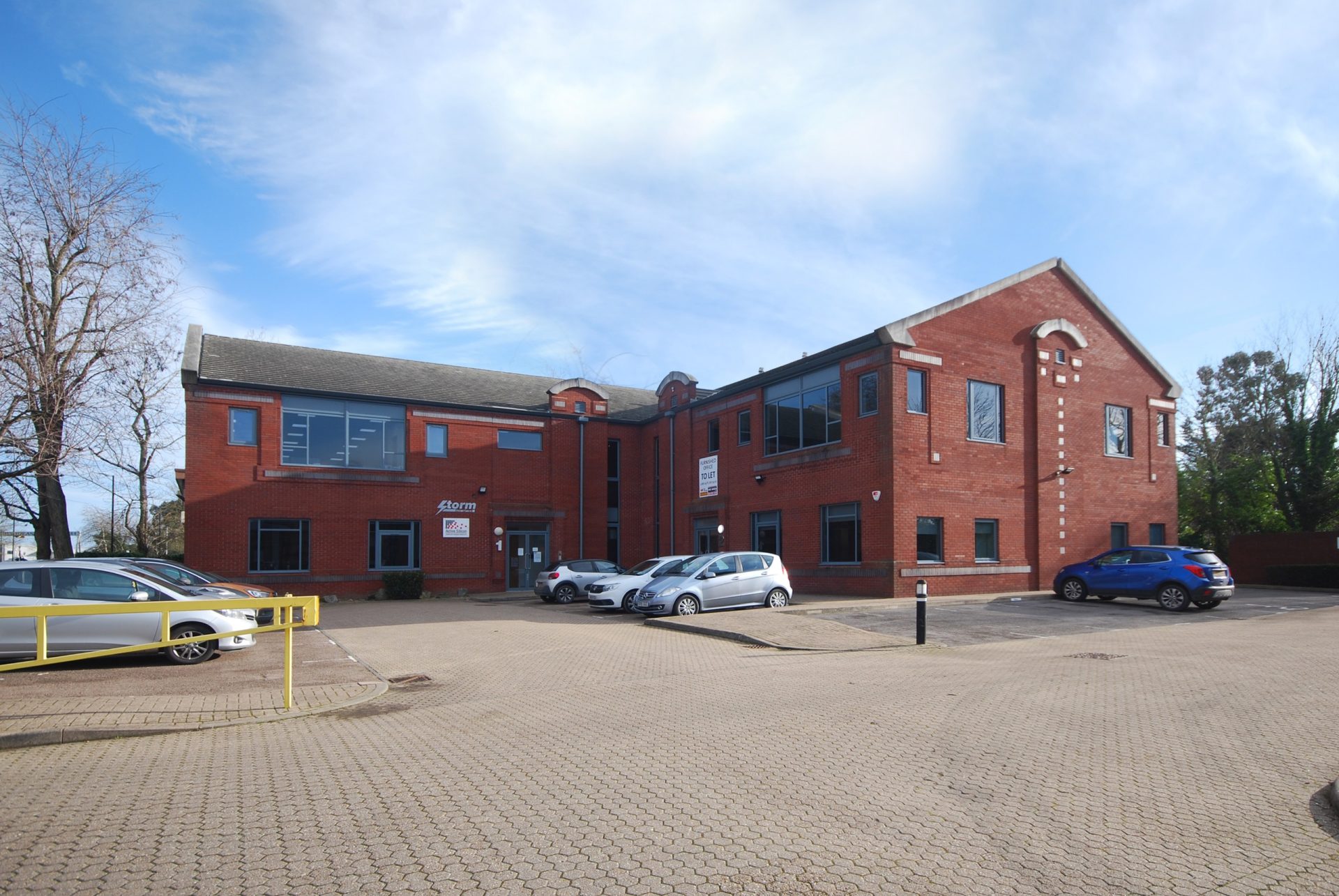 Red-brick Waterside Court office buildings with parked cars in a paved parking area in Langley, Berkshire