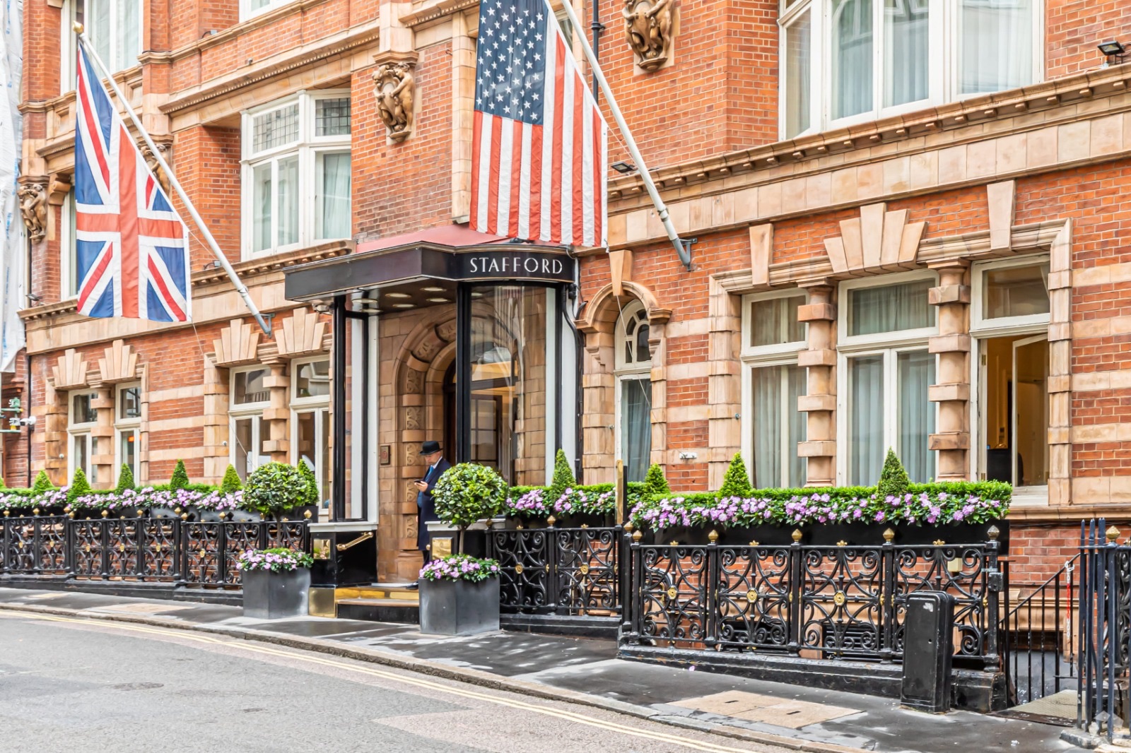 The Stafford hotel entrance in London with British and American flags displayed on its red-brick façade