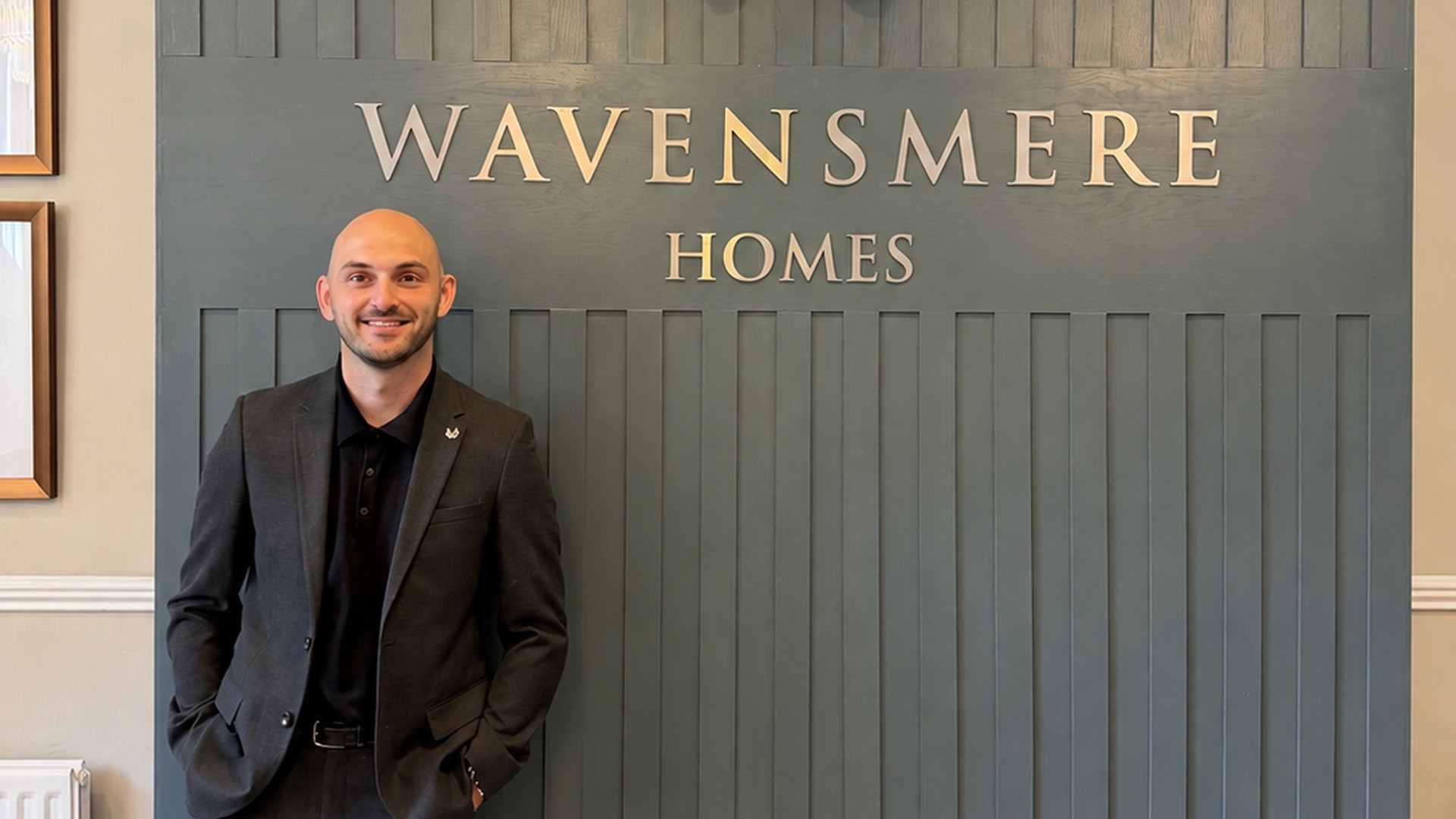 Michael Prince stands beside the Wavensmere Homes logo
