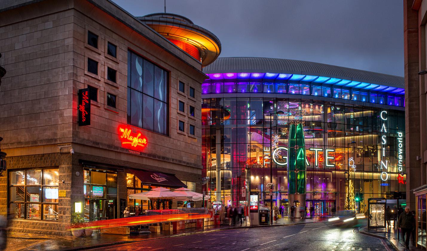 Architectural rendering of a modern entertainment complex with a cinema, shops and illuminated streetscape