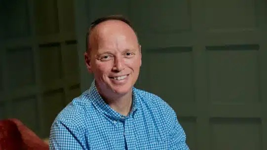 Chris Cooper, Border to Coast’s new head of real estate, smiling in a blue checkered shirt