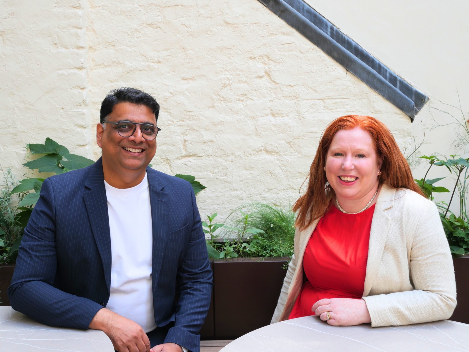 Two property professionals seated together outdoors, smiling at the camera
