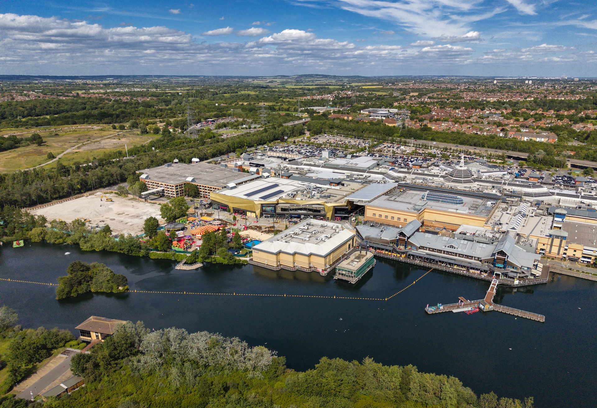 Aerial view of the Lakeside site, with the lake in the foreground and the large facility buildings beyond.