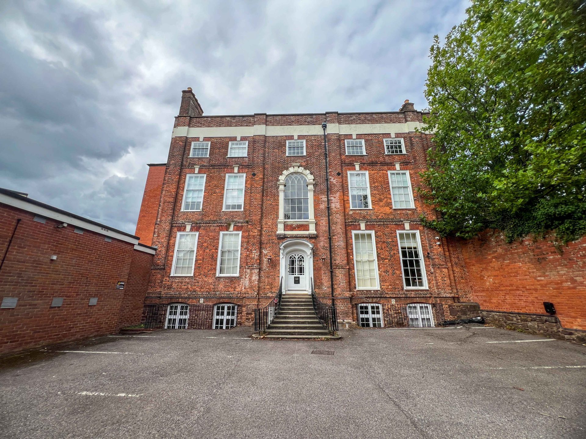 Gotham House, a red-brick Georgian townhouse with a central entrance, stands beside a large tree in Tiverton.