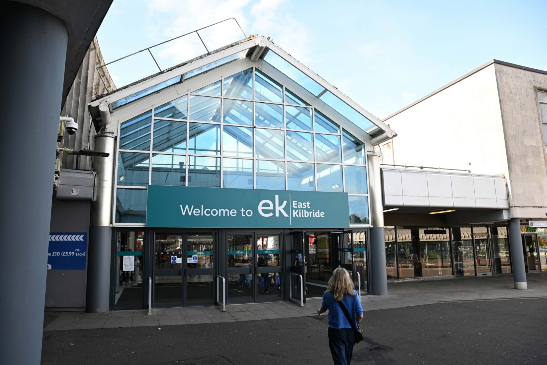 Entrance to East Kilbride shopping centre, with glass-fronted doors beneath a sign reading “Welcome to EK East Kilbride”.