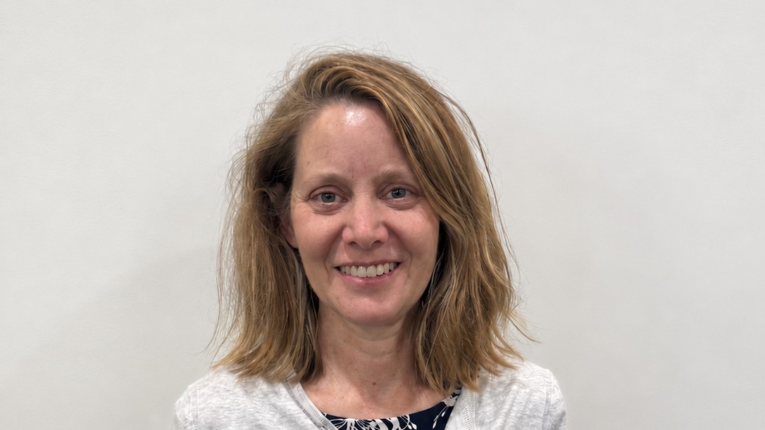 Cindy Rose smiles at the camera, wearing a light cardigan over a patterned top.