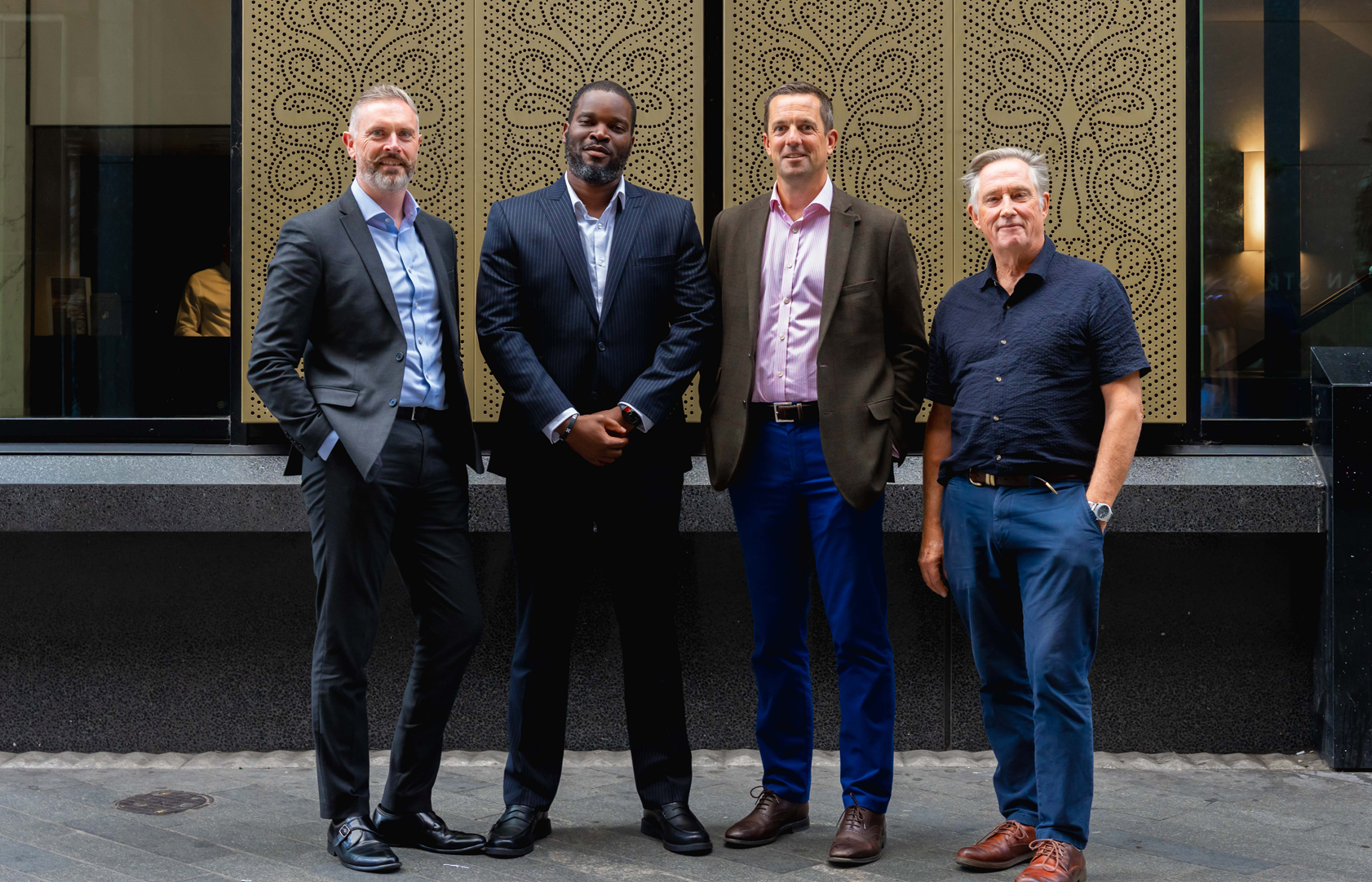 Anthony Ngwube and three colleagues stand together in a modern office lobby.