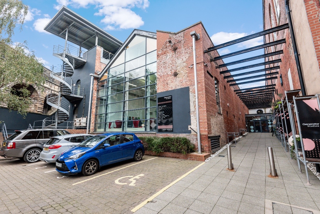 Modern commercial property with glass-fronted entrance, covered walkway and parked cars