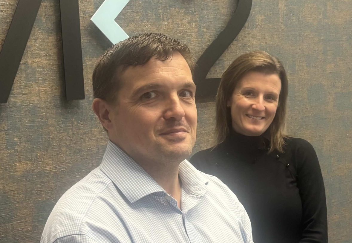 Vicky Round and a male colleague stand in front of the MK2 Real Estate logo.