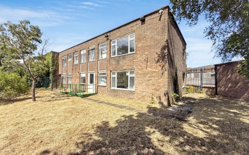 A brick built residential block with a grass lawn in front