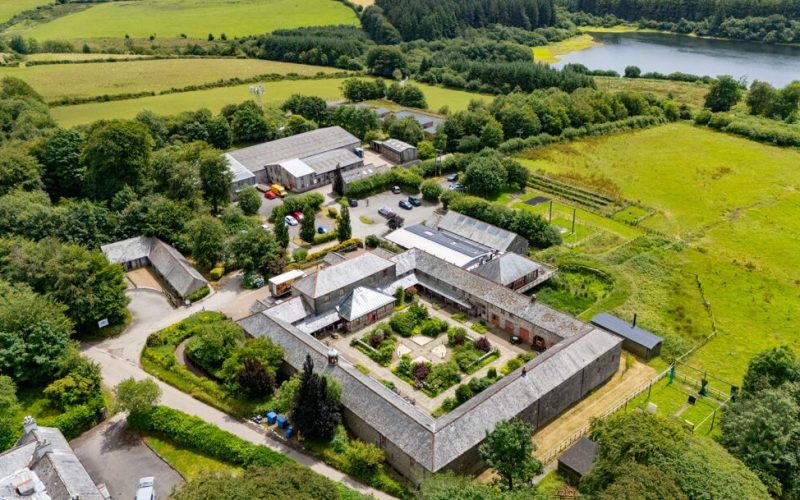 Aerial view of a complex of different buildings surrounded by green fields