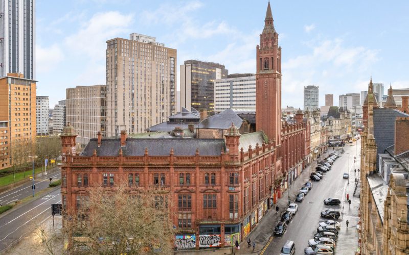Street scene with an historic red brick built building in the foreground and larger buildings to the rear