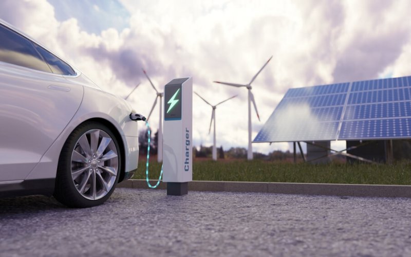 Using,Of,Charge,Station,,Solar,Panel,And,Windmill,Background.,Sustainability