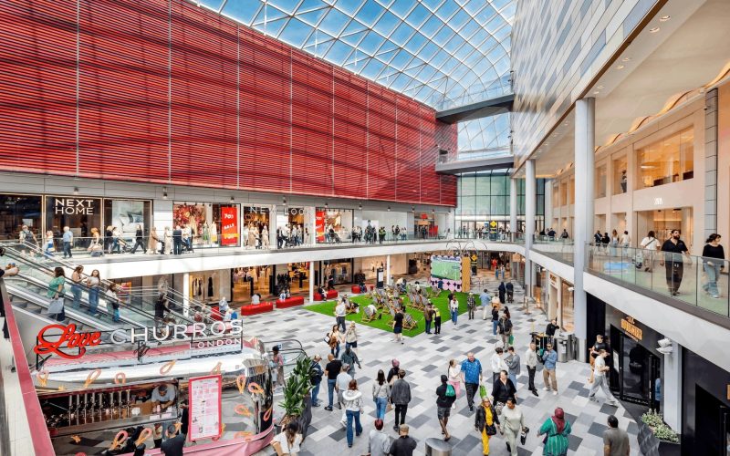Interior of a shopping centre featuring lots of shops and shoppers