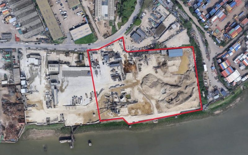 Aerial view of a wharf site marked in red alongside a river
