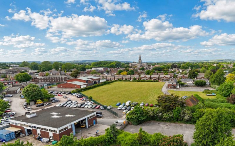 Aerial view of a large area featuring buildings and green space with Chichester cathedral in the distance