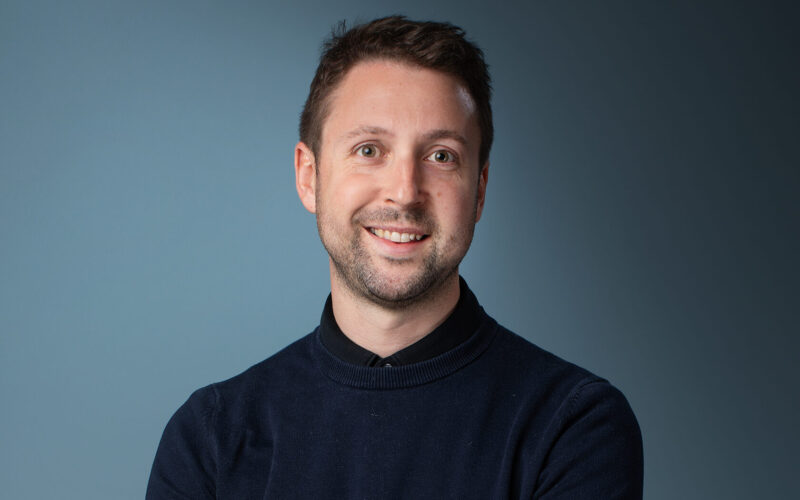 A white man with short dark hair wearing a dark shirt