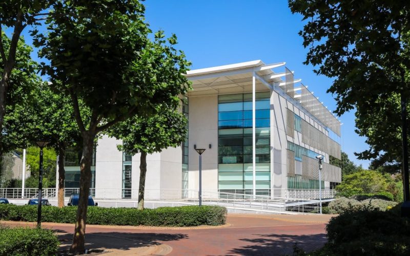 A modern white building surrounded by trees and greenery