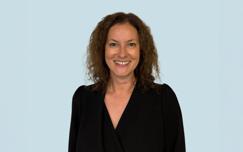 A smiling Rebecca Napier has brown curly hair and is wearing a black shirt