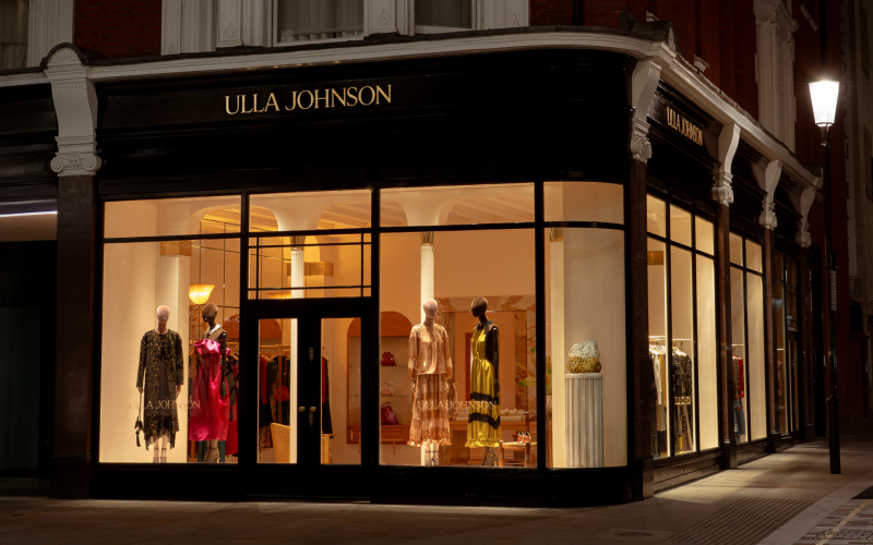 Exterior of a retail store at night featuring a sign saying Ulla Johnson