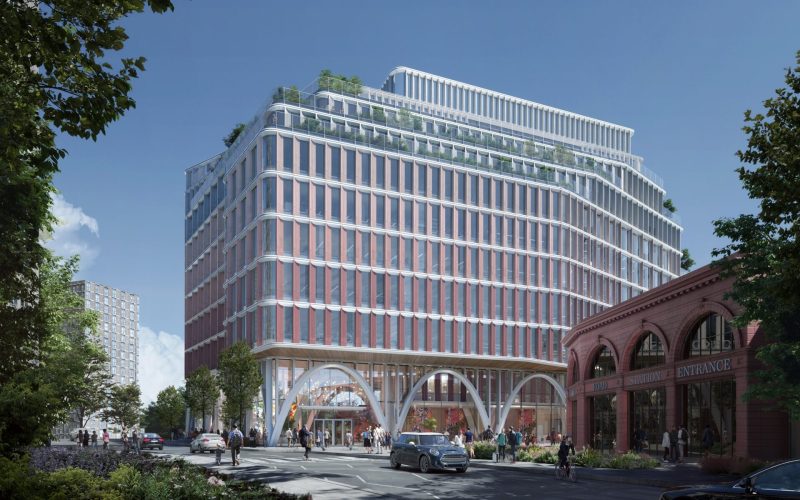 A modern office building featuring a glass and steel facade with a main road running in front