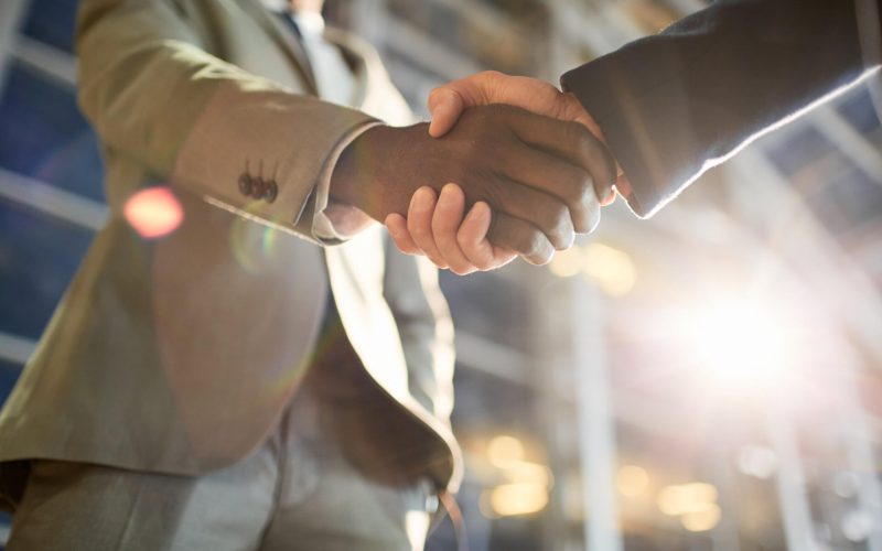 Low,Angle,Closeup,Shot,Of,Two,Business,Partners,In,Handshake: