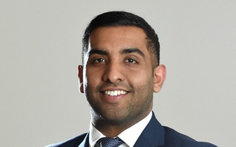 Puneet Vedhera smiling in a navy suit and tie