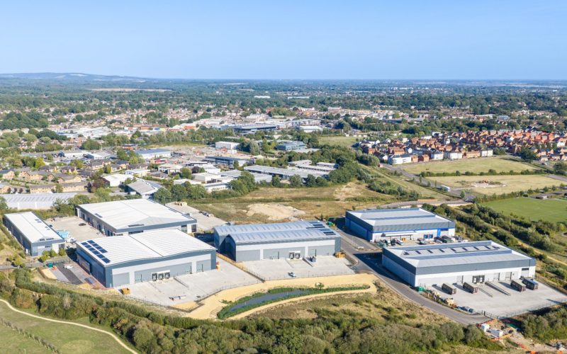 Aerial view of a modern industrial and commercial development beside housing and open fields