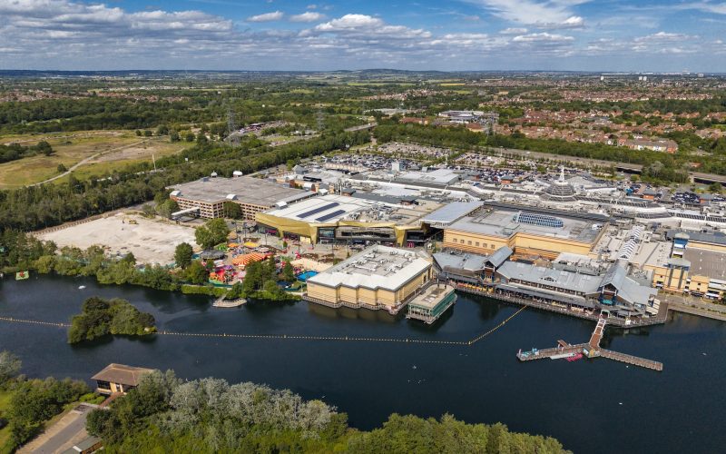 Aerial view of the Lakeside site, with the lake in the foreground and the large facility buildings beyond.