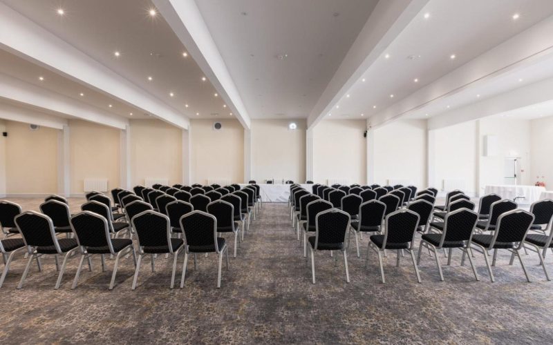 Empty conference room set with rows of chairs facing a presentation area.