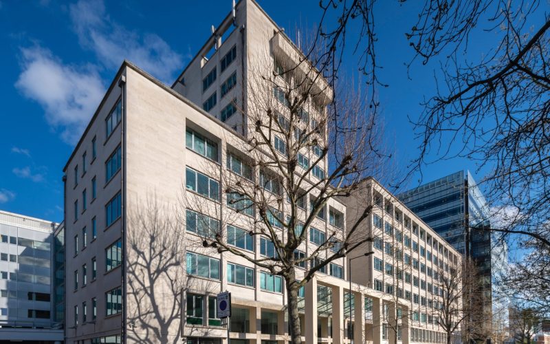 Modern multi-storey office building on a city street beneath a blue sky