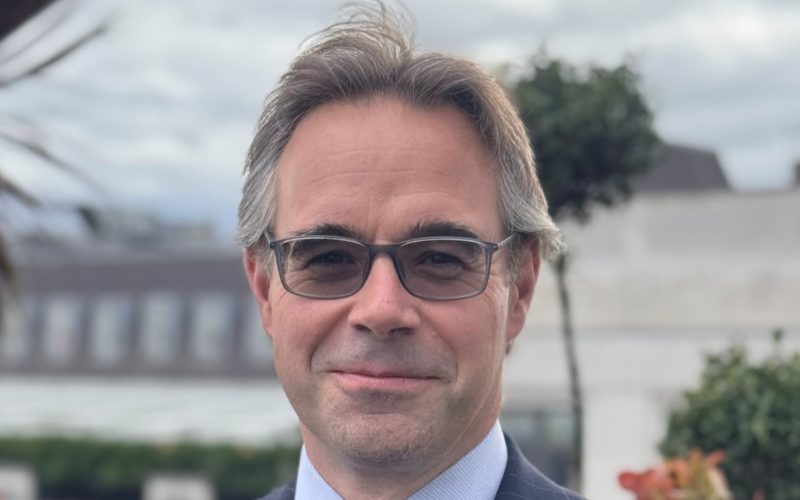 Alex Ayres, Colliers director, wearing a suit and glasses outdoors