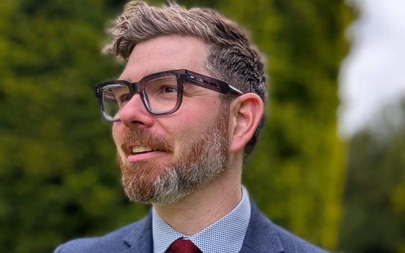 Christian Galanis, building consultancy director at Turner & Townsend, wearing glasses, a blue suit and red tie.
