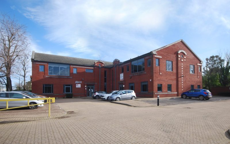 Red-brick Waterside Court office buildings with parked cars in a paved parking area in Langley, Berkshire
