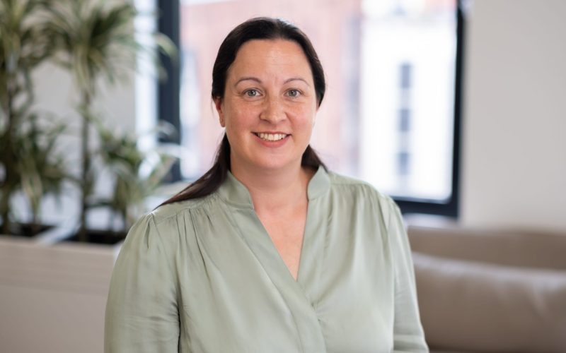 Portrait of a smiling woman in a pale green blouse in a modern office