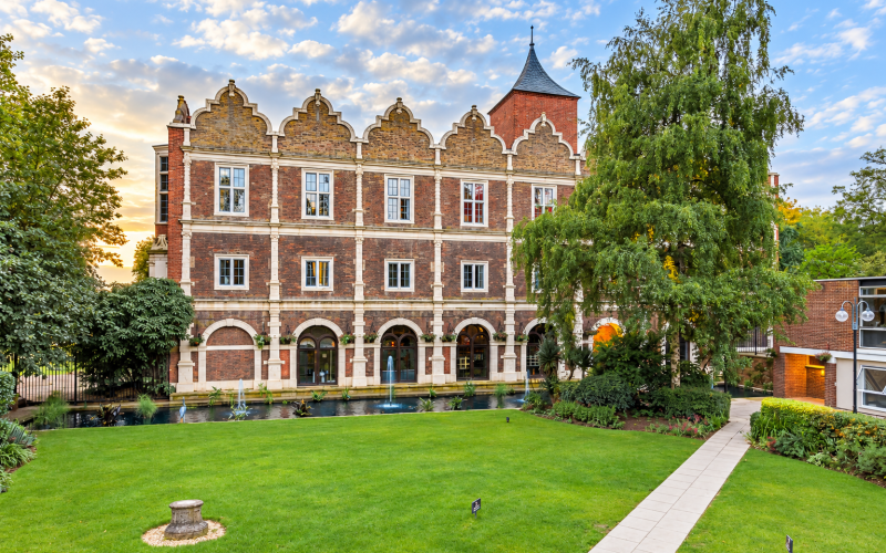 Historic Holland House building at Holland Park, with a green lawn and trees in the foreground.